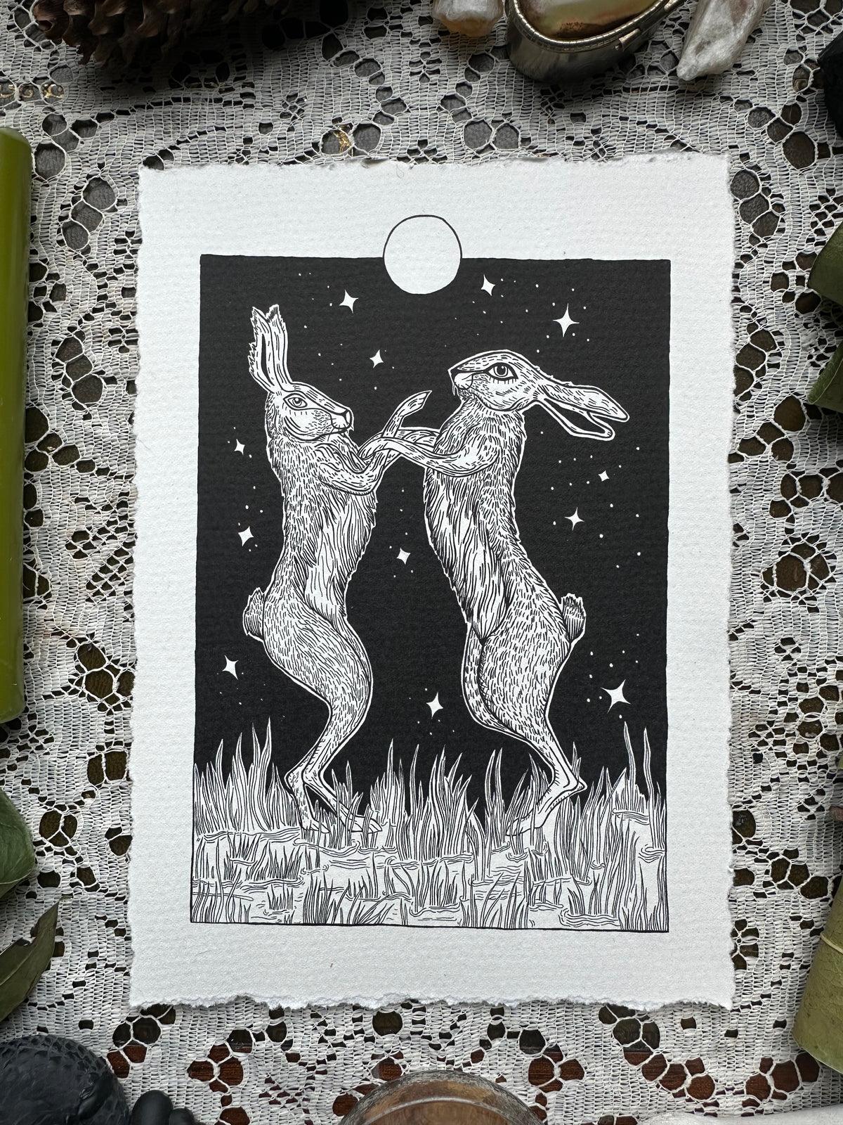 Pen and ink illustration of two hares dancing under the full moon 