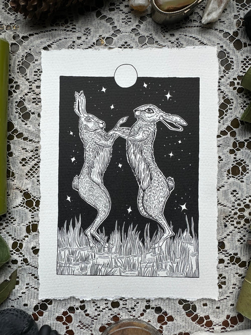Pen and ink illustration of two hares dancing under the full moon 