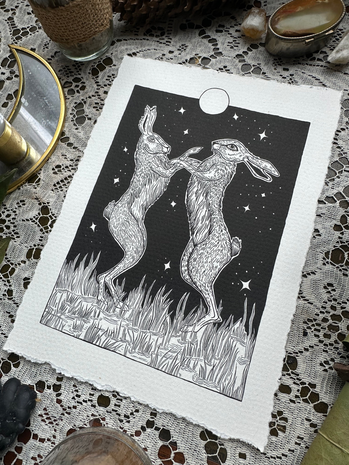 Pen and ink illustration of two hares dancing under the full moon 