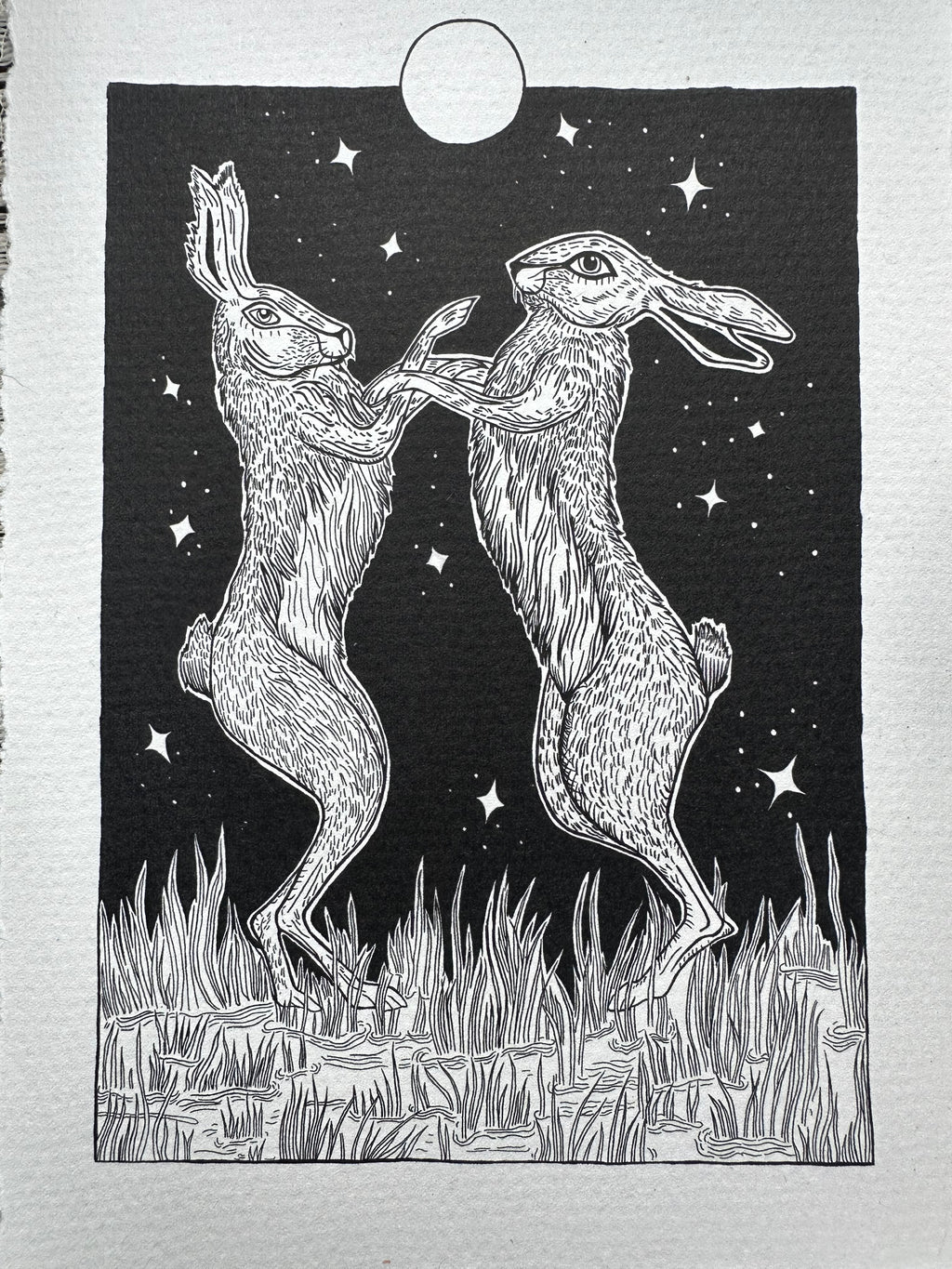 Pen and ink illustration of two hares dancing under the full moon 