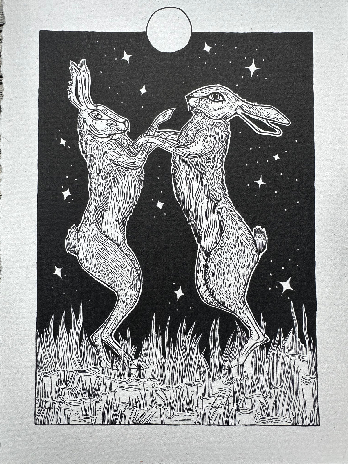 Pen and ink illustration of two hares dancing under the full moon 